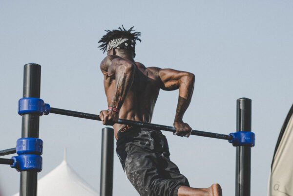 Athletic shirtless man performing pull-ups outdoors