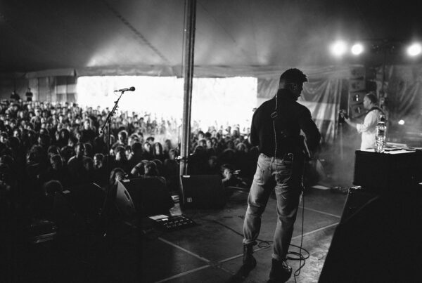 Musician performing to packed crowd inside tent