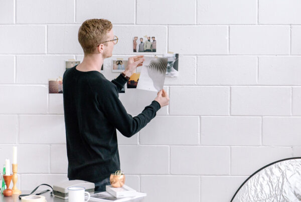Man arranging photos on white brick wall