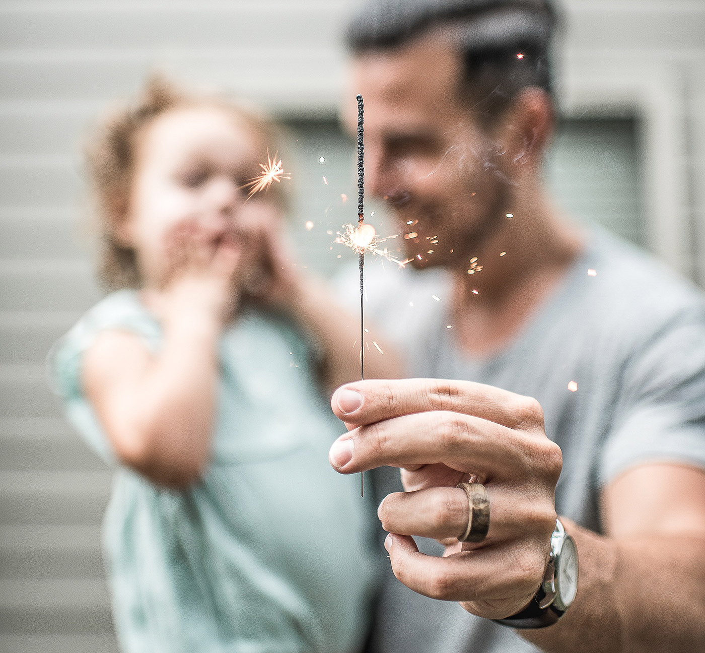 Man holding lit sparkler with excited child